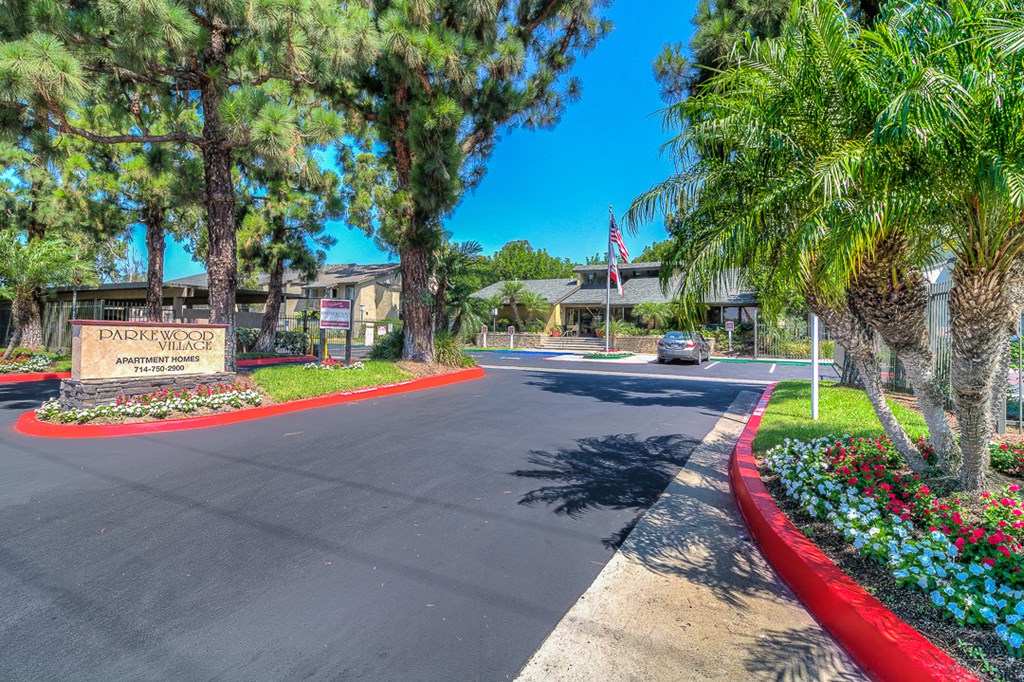 a street with palm trees and a building with a car driving down the street